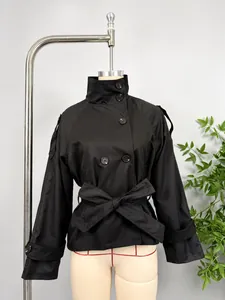 Detail view of black double-breasted short trench coat with elegant waist tie belt