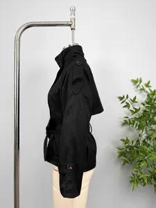 Side view of black short trench coat featuring a belted waist and buttoned cuffs details