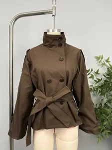 Detail view of a stylish brown double-breasted belted short trench coat on a mannequin.