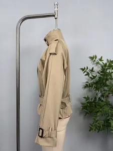 Side view of beige short trench coat featuring belted waist and shoulder epaulets