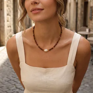Close-up of a Bohemian tiger eye beaded necklace featuring a central baroque pearl.