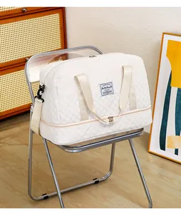Nahaufnahme einer weißen gesteppten Reisetasche mit Trocken-Nass-Trennung auf einem Stuhl
