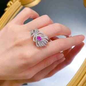 Close-up of an elegant S925 silver feather ring with a vibrant pink gemstone on a finger.