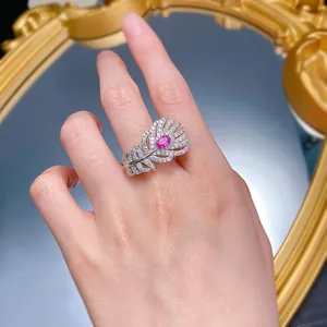 Detailed view of an elegant silver feather ring with a pink stone worn on a hand.