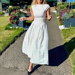 Mannequin portant une robe d'été blanche à pois sans manches dans un jardin ensoleillé