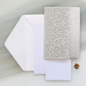 Detail view of silver glitter laser-cut wedding invitation with envelope and inserts