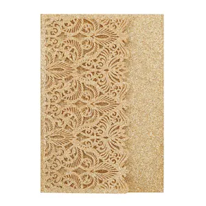 Close-up of golden glitter invitation card with intricate laser-cut floral pattern