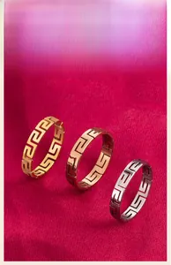 Detailed view of titanium steel rings featuring a Greek key meander pattern in three colors.