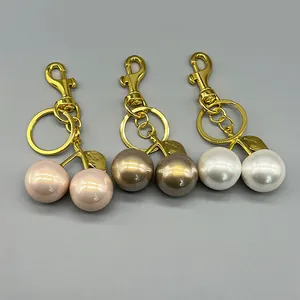 Macro view of luxury cherry bag charms featuring glossy pearls and golden metal hardware