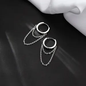 Primo piano di orecchini a cerchio in argento con nappe a doppia catena su sfondo nero.