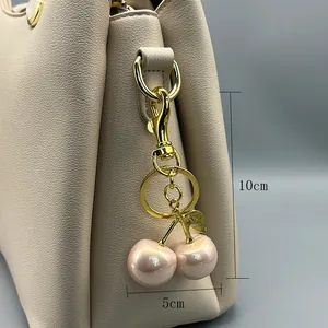 Detail view of pink pearl cherry bag charm with gold hardware and dimensions