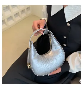Detailed view of a stylish silver crescent handbag featuring premium crocodile skin embossing.