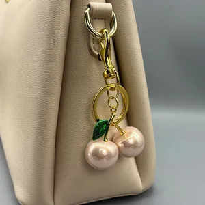 Detailed close-up view of a pink pearl cherry bag charm featuring gold-tone metal hardware