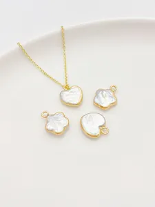 Detalle macro de dijes de perlas barrocas de corazón y flores con cadena de oro en cerámica