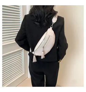 Back view of a beige PU leather chest bag with decorative tassels on a black blazer jacket