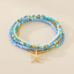 Primer plano de tobillera bohemia de varias capas con cuentas azules y estrella de mar.