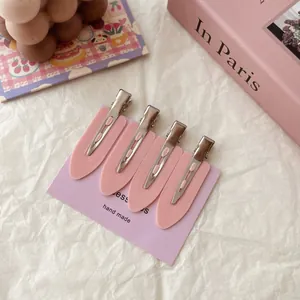 Close-up view of four pink no-mark alligator hair clips arranged on a purple display card
