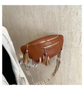 Macro view of brown PU leather chest bag featuring tassels and geometric patterned strap