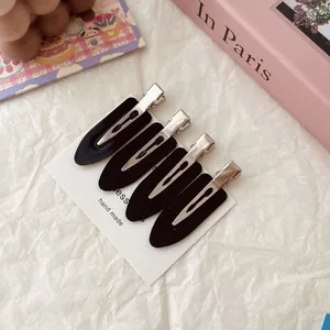 Set of four black seamless alligator hair clips on a white handmade display card