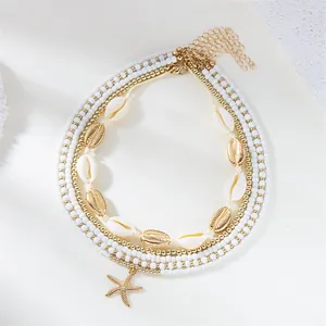 Detailed view of bohemian 5-piece necklace set with white beads, shells and starfish charm.