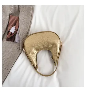 Close-up of gold crocodile-textured crescent bag with metallic finish.