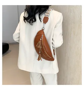 Rear view of a chic brown PU leather chest bag with tassels and a patterned wide strap.