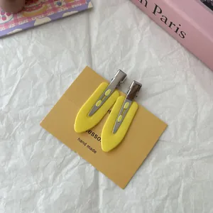 Macro view of bright yellow no-trace duckbill hair clips on a handmade card.