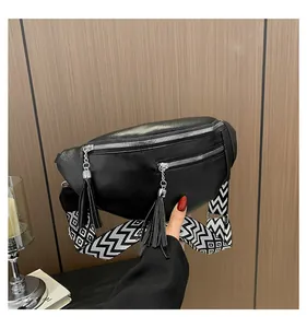 Close-up of black PU leather chest bag with stylish tassels and wide patterned strap.