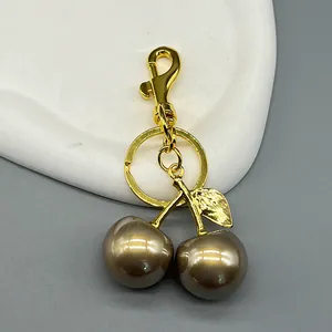Detailed view of luxury cherry keychain with gold-plated leaf and pearlized brown charms