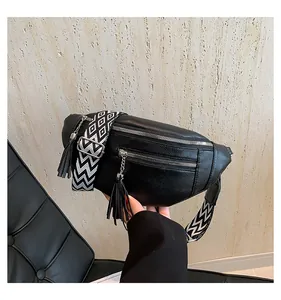 Close-up detail of a black PU leather chest bag featuring a patterned strap and tassels