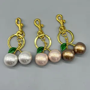 Detailed view of three luxury pearlescent cherry keychains in white, pink, and bronze