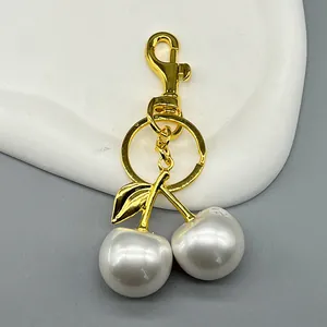Detailed macro shot of a golden cherry keychain with two elegant white pearls