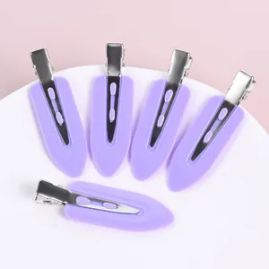 Detail view of five purple creaseless makeup hair clips on a soft pink background