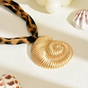 Vista ravvicinata di una collana con ciondolo a conchiglia dorata e laccio leopardato.