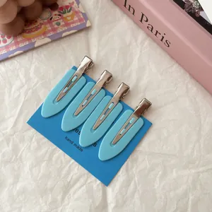 Detailed view of four light blue non-trace duckbill hair clips on blue card packaging
