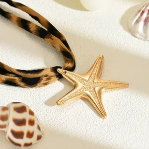 Primo piano di una collana con ciondolo a stella marina dorata e cordino in tessuto leopardato