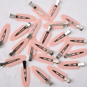 Close-up of pink no-crease hair clips with silver metal duckbill clips on a soft background.