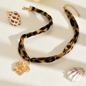 Dettaglio di una collana girocollo in tessuto leopardato con ciondolo a fiore dorato