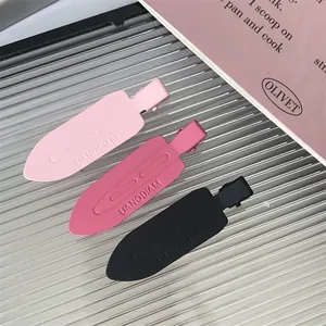 Close-up of three matte knife-blade hair clips in pink and black colors with text.