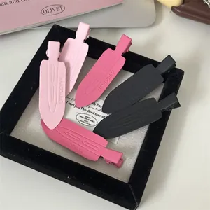 Collection of matte pink and black no-trace duckbill hair clips in a jewelry tray