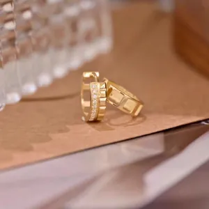 Close-up of geometric gold hoop earrings with sparkling diamond accents