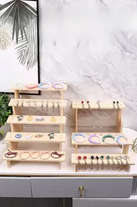 Espositore in legno a gradini per orecchini e braccialetti su una scrivania bianca