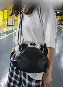 Detailaufnahme einer schwarzen Umhängetasche in Krabbenform mit Kussverschluss im Streetstyle.