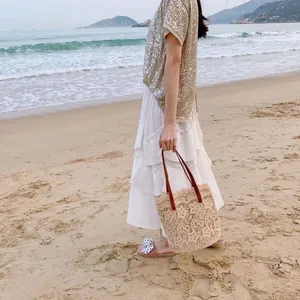 Detailaufnahme einer böhmischen Spitzen-Stroh-Strandtasche mit eleganten Ledergriffen