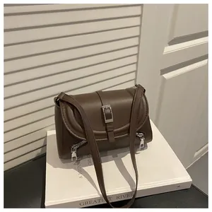 Vintage brown faux leather shoulder bag featuring buckle strap and silver zippers on top of book