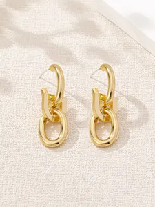 Close-up detail of golden minimalist earrings with interlocking oval and square links