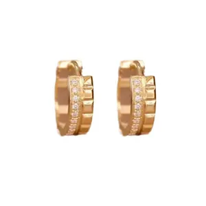 Close-up of gold hoop earrings with square block texture and inlaid small diamonds