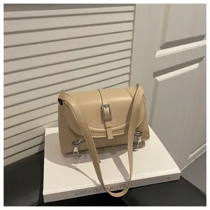 Detail view of a beige retro crossbody bag with silver zipper accents on a white book.