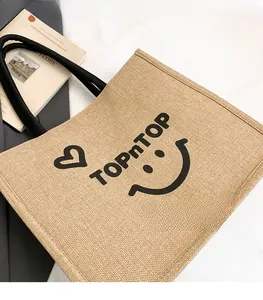 Detail shot of a textured jute tote bag with a black smiley face and TOPnTOP print