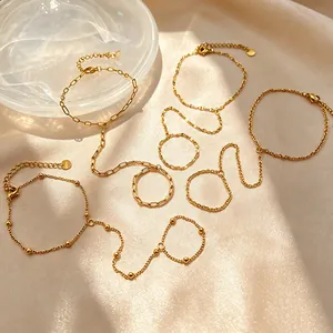 Detailed view of four gold-plated stainless steel finger chain bracelets on satin